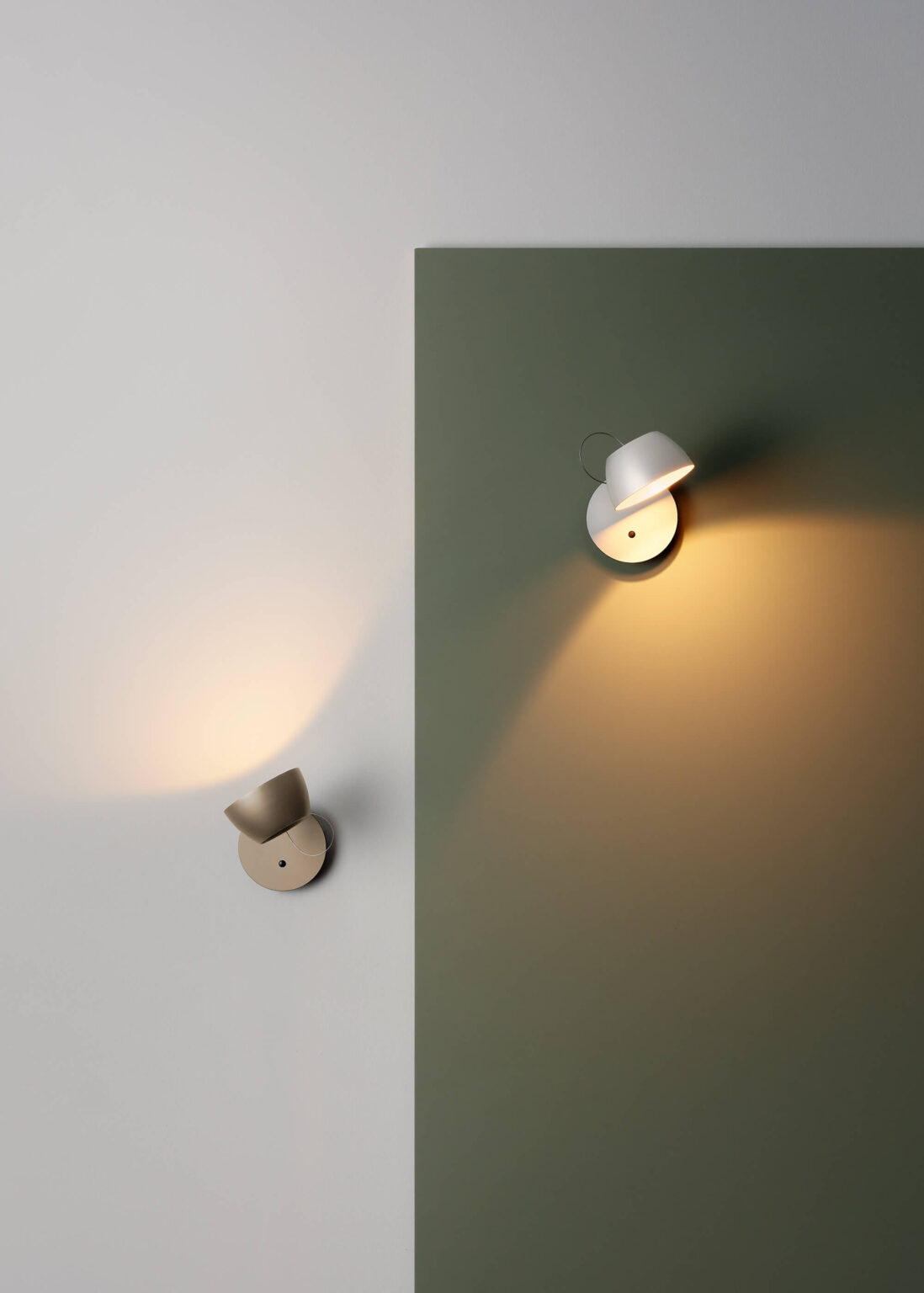 Zwei Baltensweiler Leuchte als Wandleuchten setzen warmes Licht auf grüner und weisser Wandfläche.