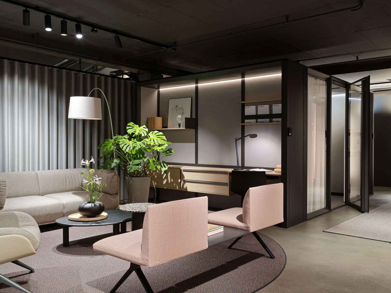 teo jakob Showroom, Gerechtigkeitsgasse 36 Bern, Lounge mit Sofa, Stehleuchte, Pflanzen und Arbeitsplatz im Hintergrund in einem modernen Showroom.