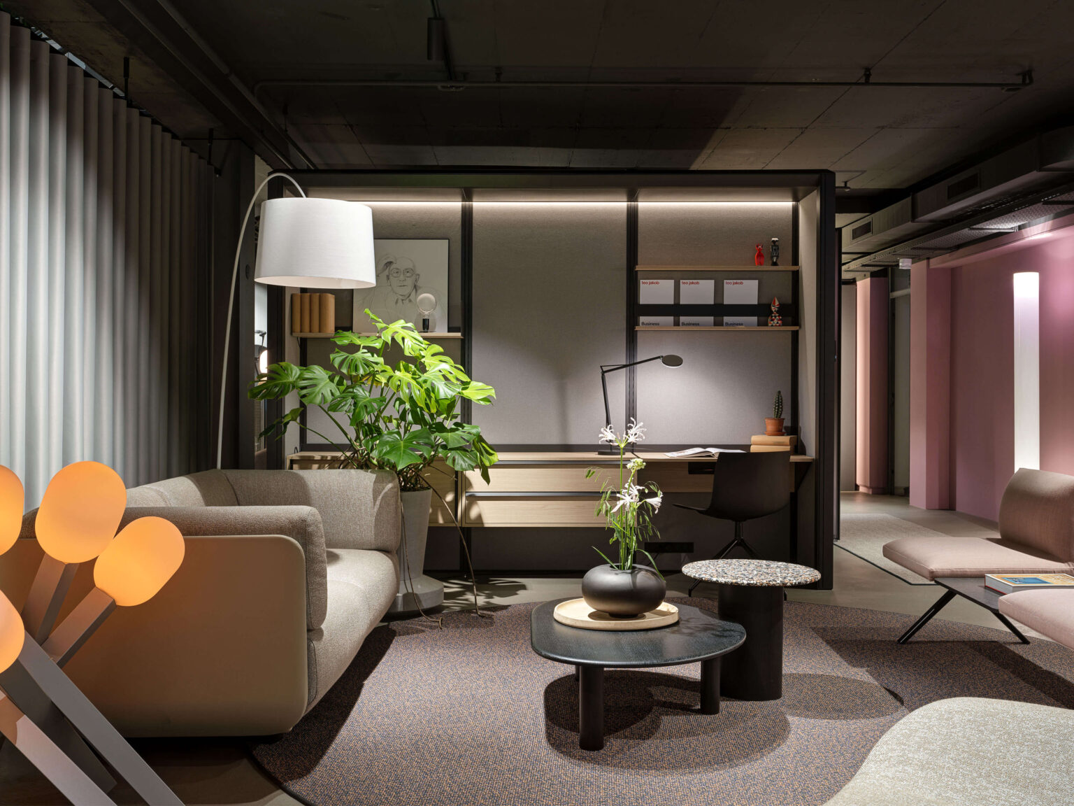 teo jakob Showroom, Gerechtigkeitsgasse 36 Bern, Lounge mit Sofa, Stehleuchte, Pflanzen und Arbeitsplatz im Hintergrund in einem modernen Showroom.