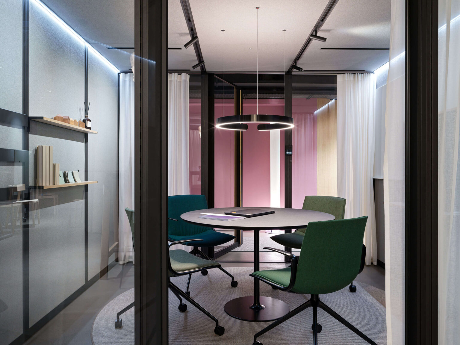 teo jakob Showroom, Gerechtigkeitsgasse 36 Bern, verglaster Meeting Pod mit rundem Tisch, vier grünen Drehstühlen und Ring Pendelleuchte.