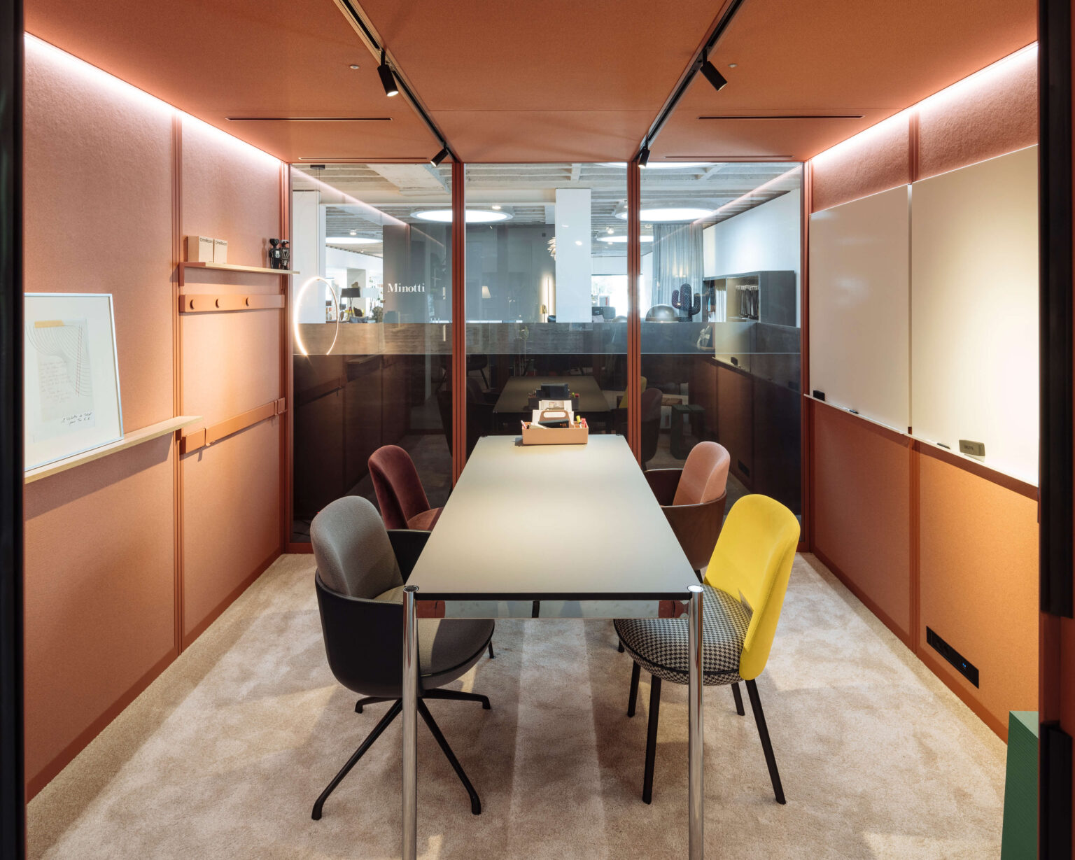 Beratungsraum im Showroom teo jakob Genf mit farbigen Stühlen und Glaswand.