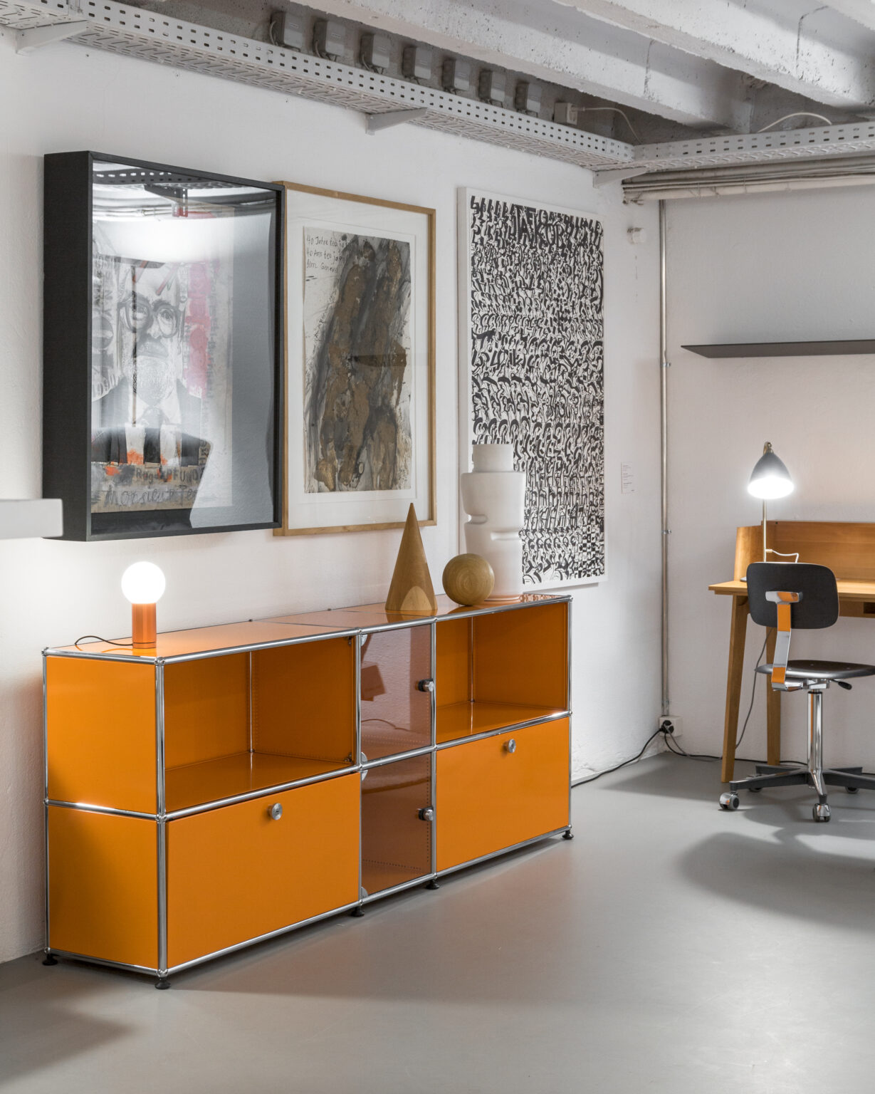 USM Sideboard in Orange mit Kunstwerken im Showroom teo jakob Genf.