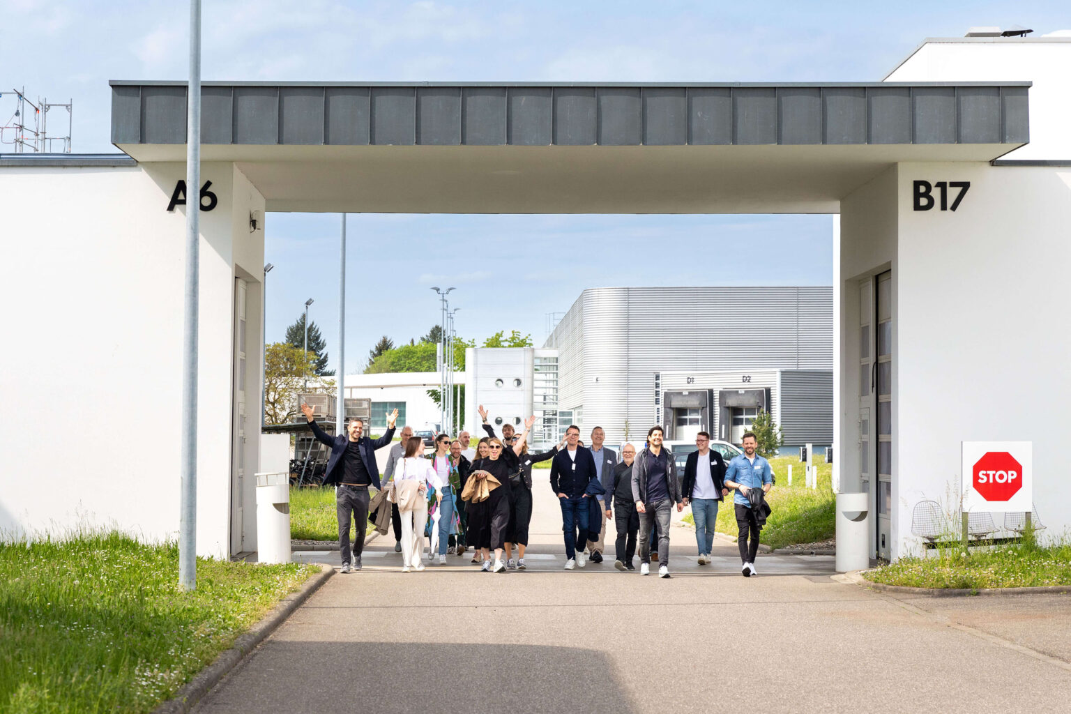 Gruppe von Personen unter Torbogen zwischen Industriegebäuden.