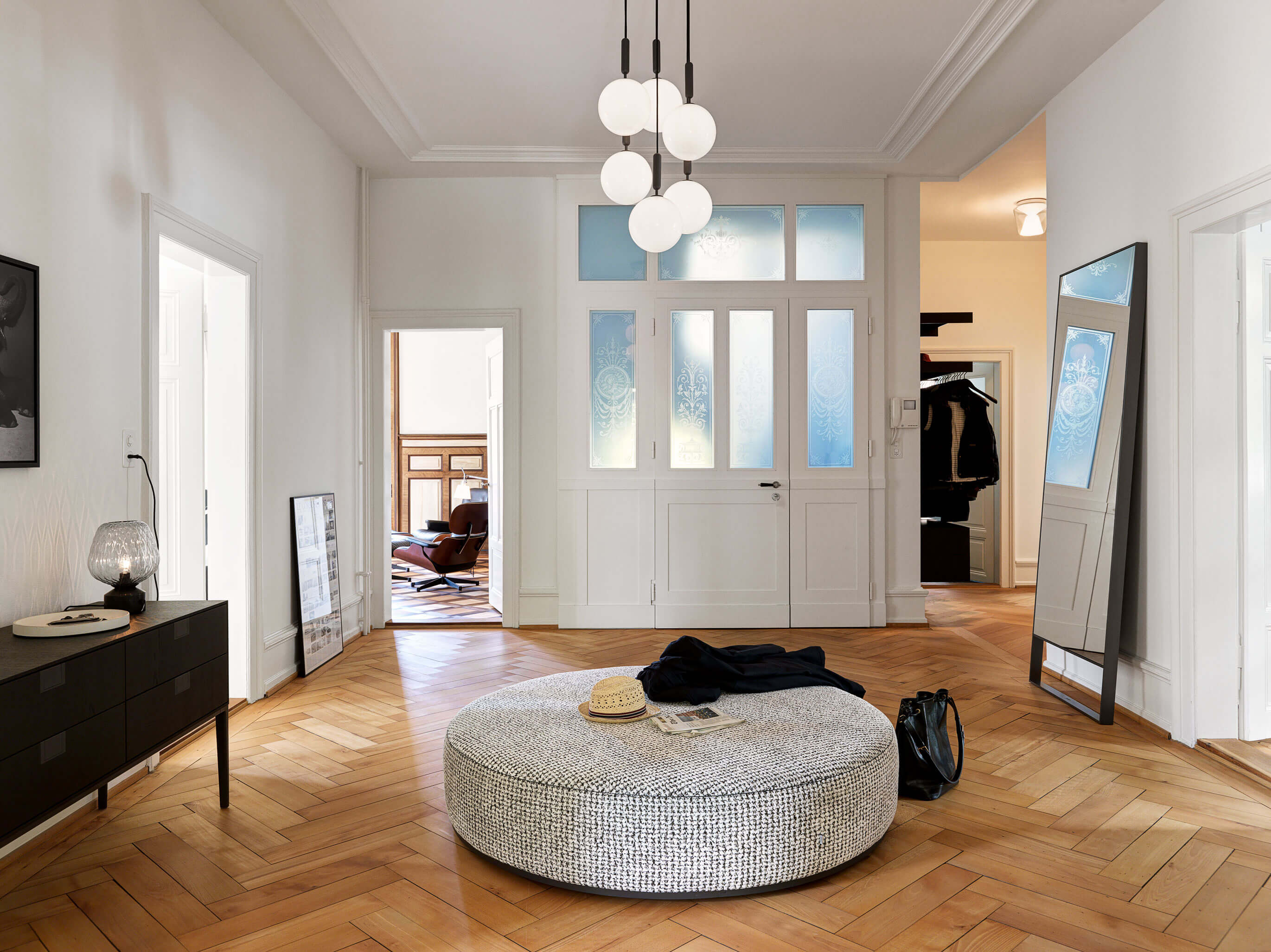 Eingangsbereich mit rundem Pouf und Spiegel in einer Altbauwohnung in Zürich