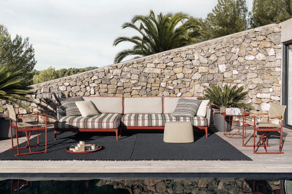 Outdoor Lounge vor Natursteinmauer mit Palmen.