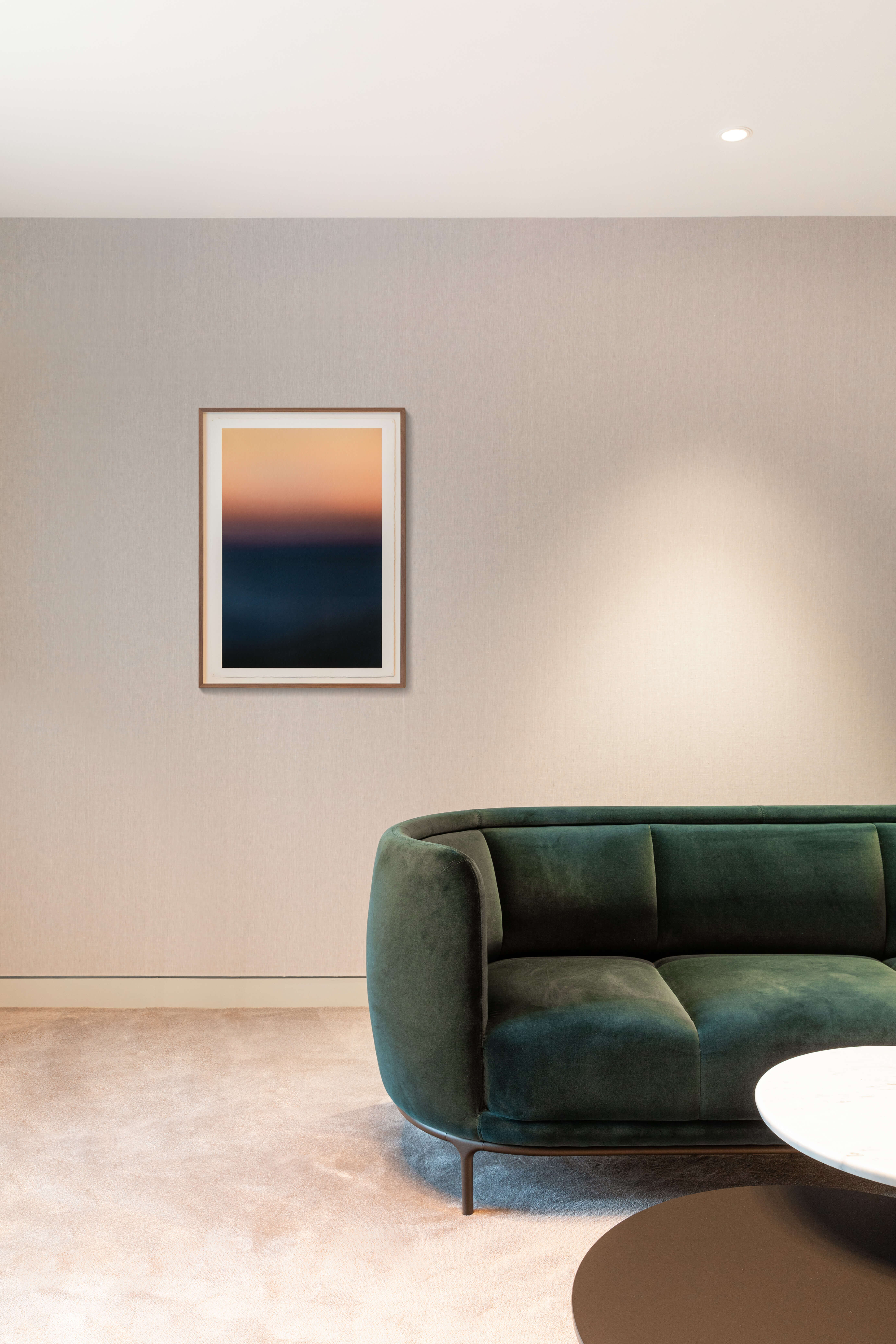 Lounge mit grünem Samtsofa, weichem Teppich und abstraktem Wandbild in einer Privatbank in Genf.