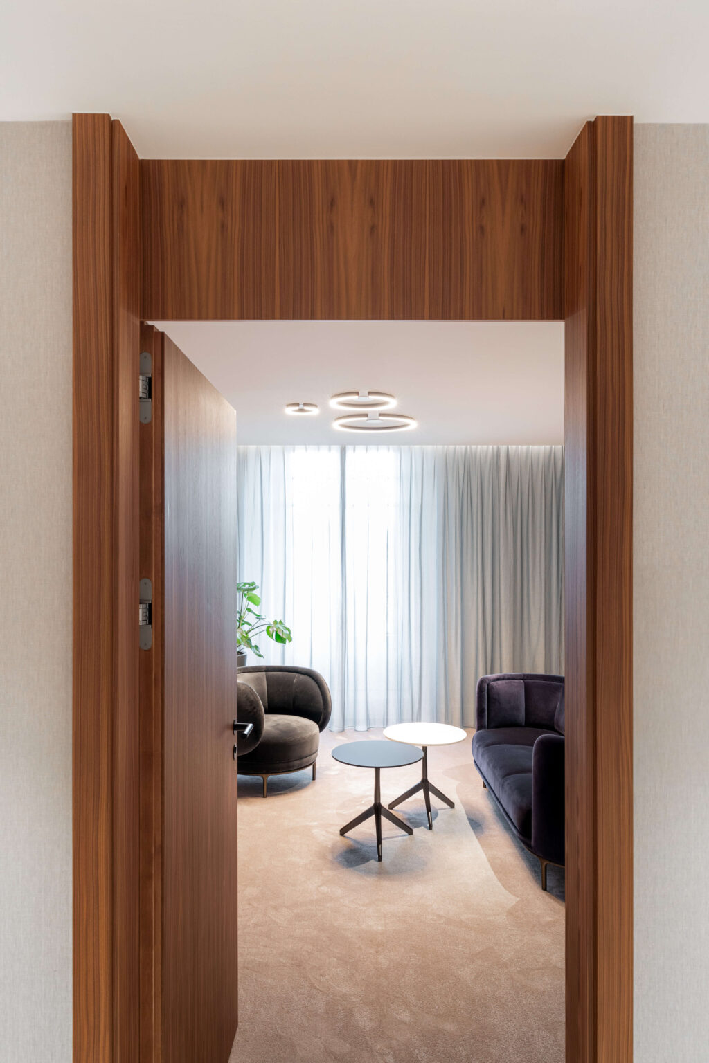 lick durch einen Holzrahmen in eine Sitzlounge mit Deckenleuchten und runden Tischen in einer Privatbank in Genf.
