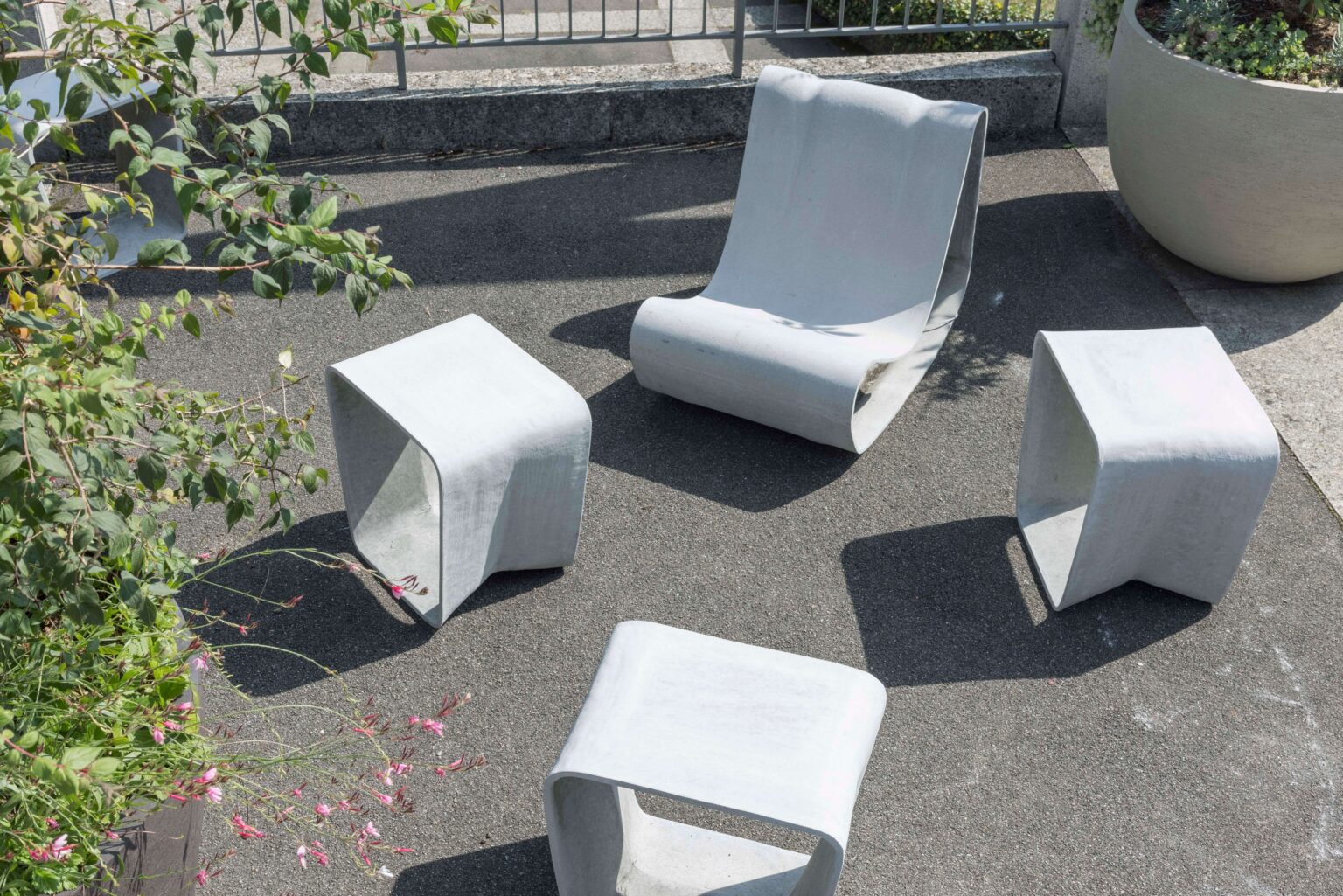 Sitzgruppe aus skulpturalen Betonelementen – Loungechair und Hocker – zwischen Pflanzkübeln bei der Friedenskirche in Bern.