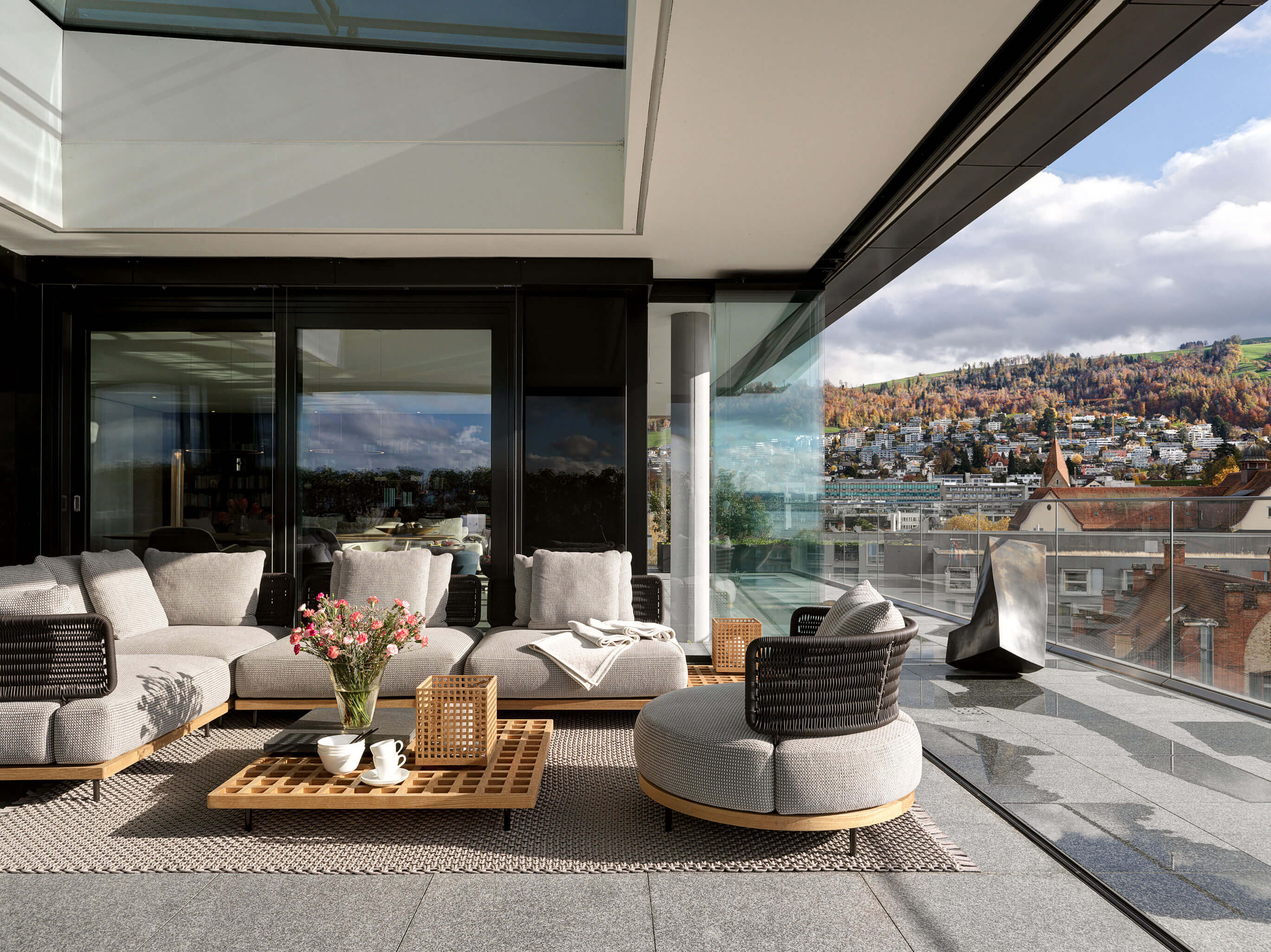 Möblierte Terrasse mit grauer Outdoor-Lounge und Glasbrüstung, Blick über die Stadt Zug.
