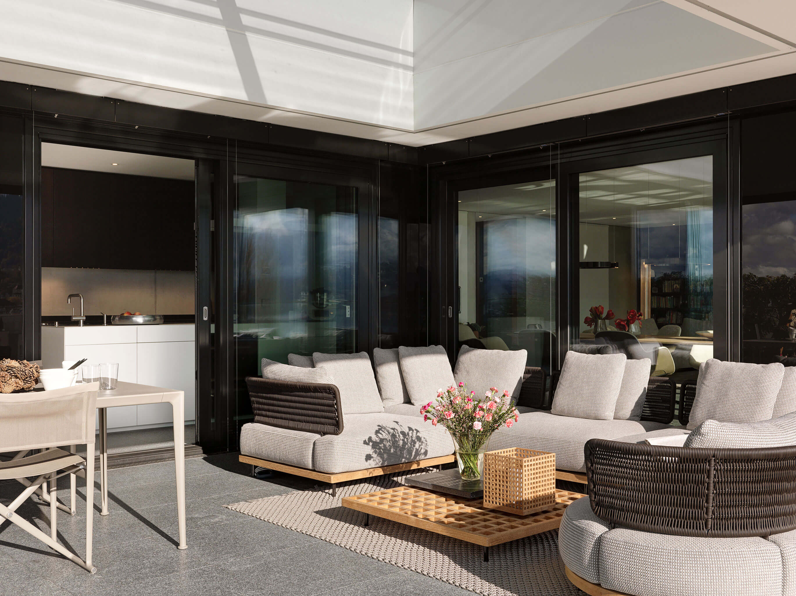 Übergang von der möblierten Terrasse zum Wohn- und Essbereich durch raumhohe Schiebetüren in einer Stadtwohnung in Zug.