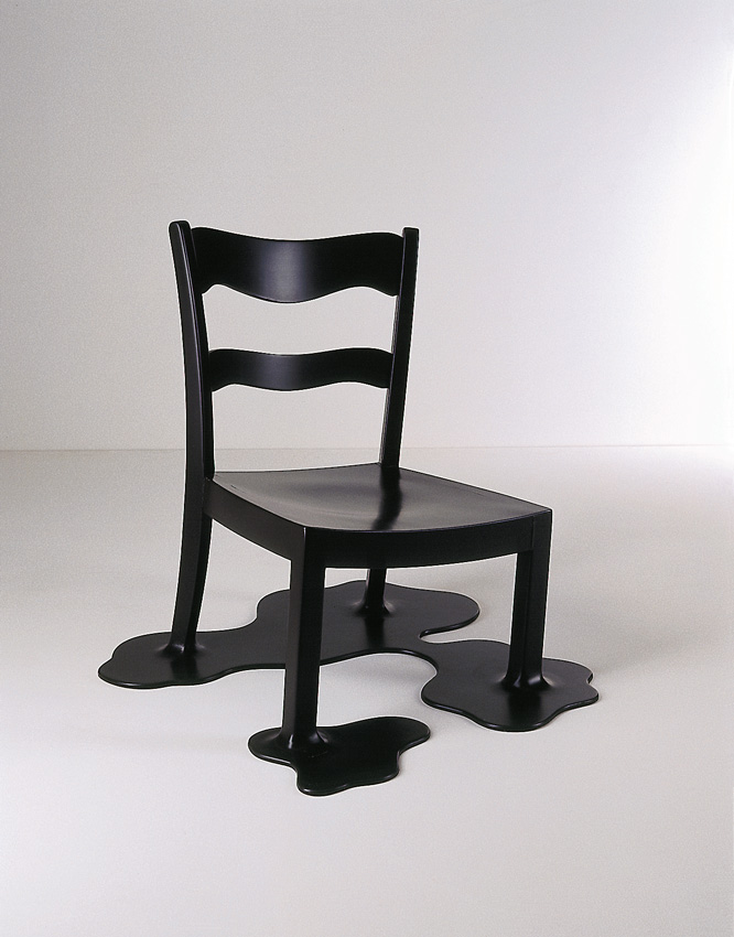 Schwarzer Stuhl als skulpturales Objekt. Beine stehen auf organischen, pfützenartigen Platten, als würde der Stuhl schmelzen.