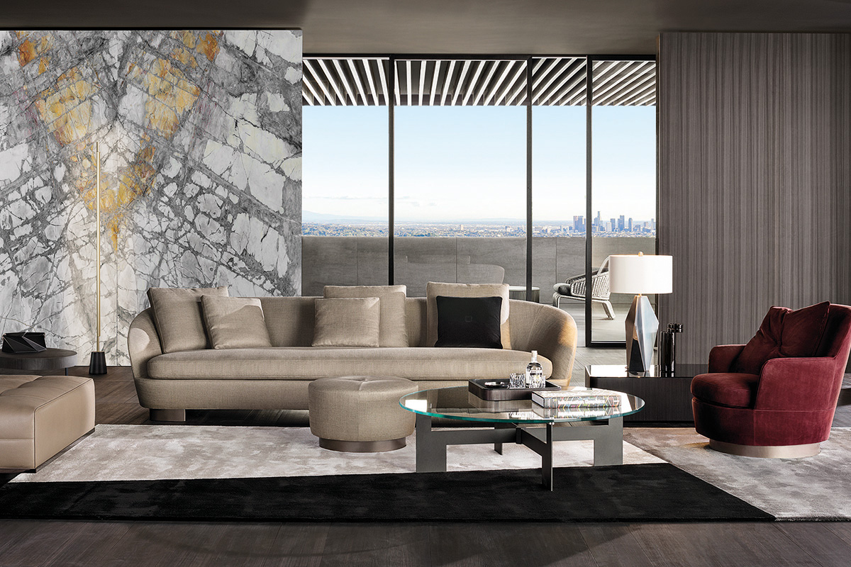 Modernes Wohnzimmer mit beigem Sofa vor markanter Marmorwand, runder Glas Couchtisch auf Teppich, roter Lounge Sessel und Stehleuchte, dahinter bodentiefe Fenster mit Balkon und Skylineblick.