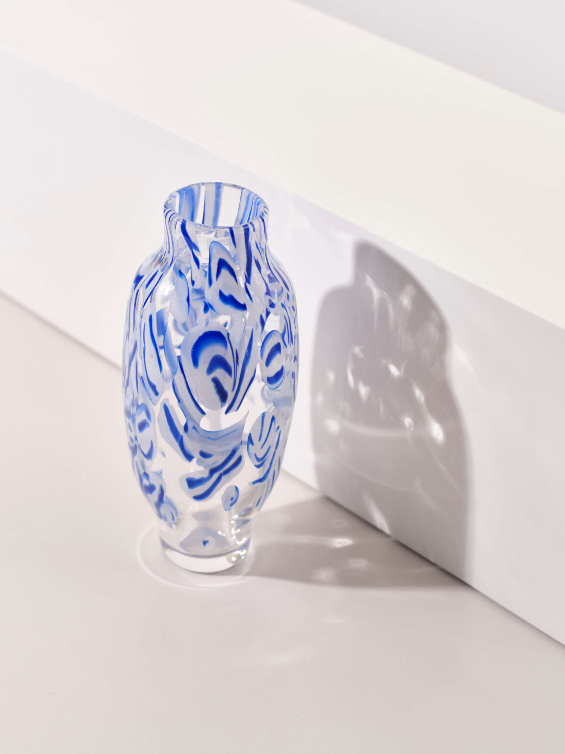 Transparente Vase mit blauen Mustern im Sonnenlicht.