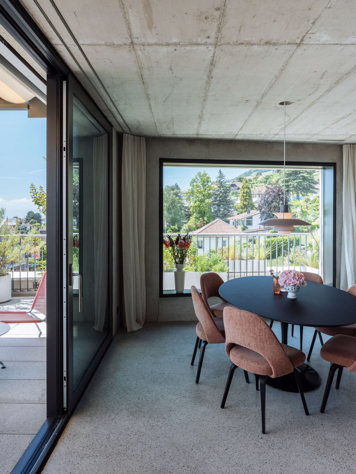 Essbereich mit rundem Tisch und Blick auf Terrasse und Hanglage.