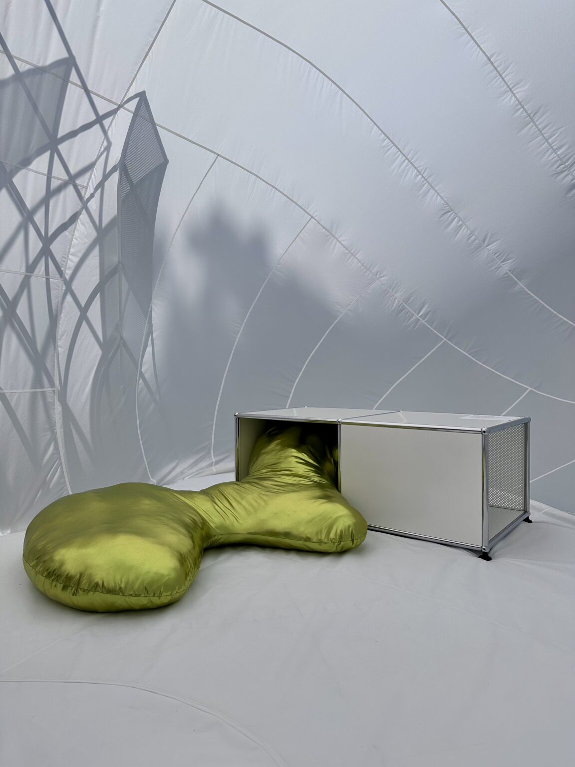 Skulpturale Sitzlandschaft mit grünem Polster neben modularem Möbel.