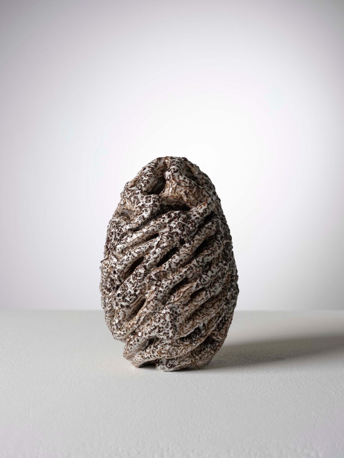 Organische Keramikskulptur von Raphaël Emine mit weisser, gesprenkelter Glasur, dunklen Einschlüssen und geschichteter, durchbrochener Struktur.