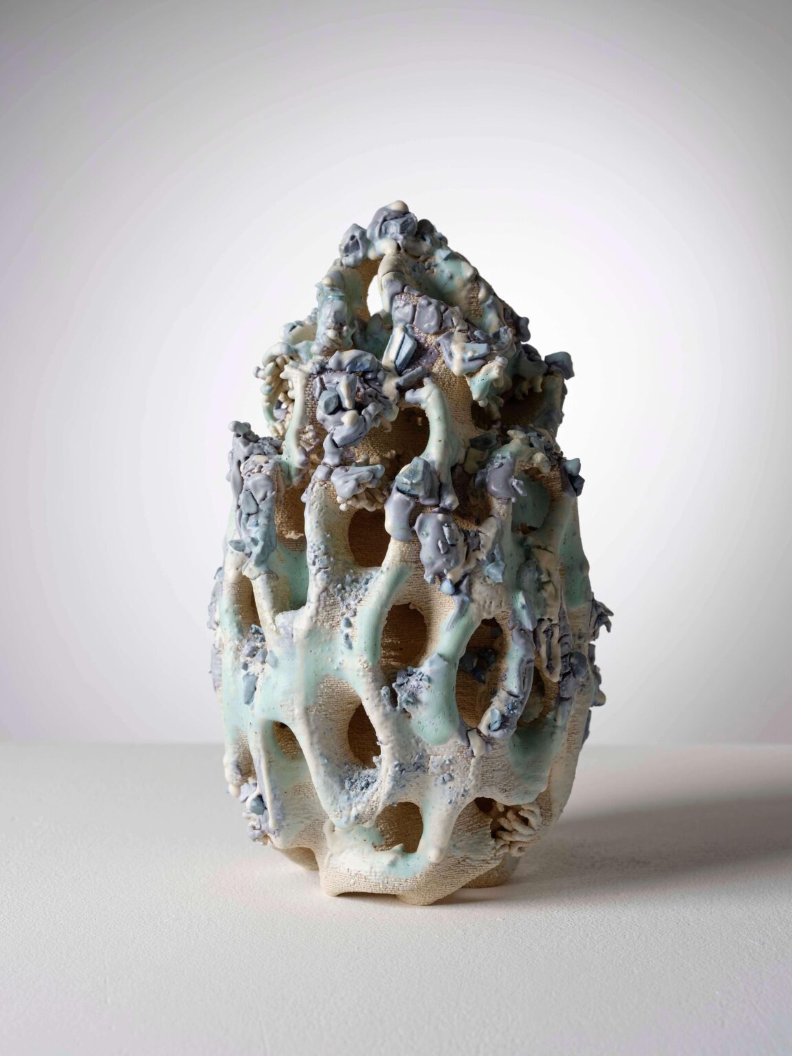 Organische Keramikskulptur von Raphaël Emine mit durchbrochener Struktur, hellblauer Glasur, grauen Akzenten und stark plastischer Oberfläche.