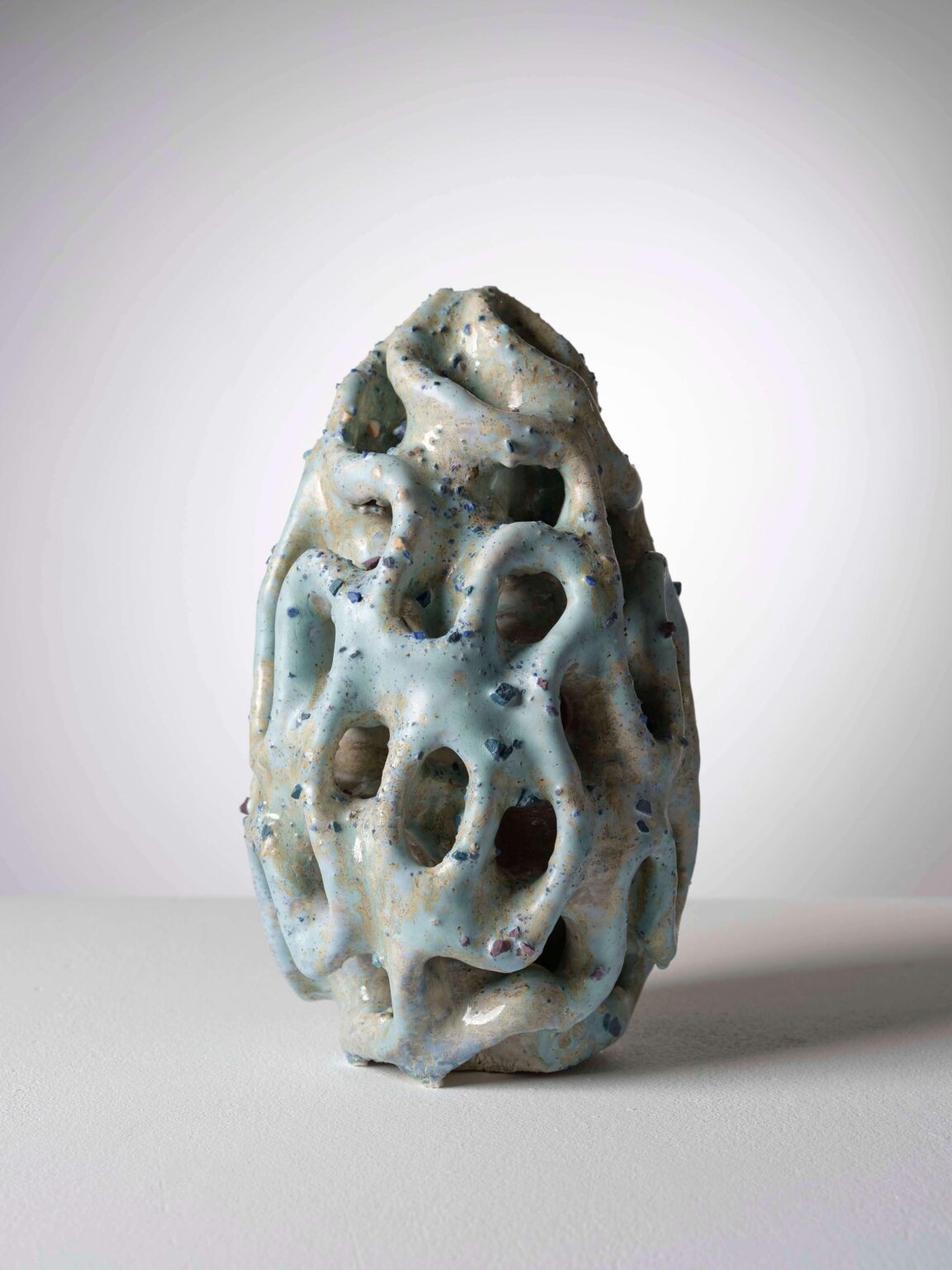 Organische Keramikskulptur von Raphaël Emine mit glänzender, hellblauer und cremefarbener Glasur, durchbrochener Struktur und fliessenden Formen.