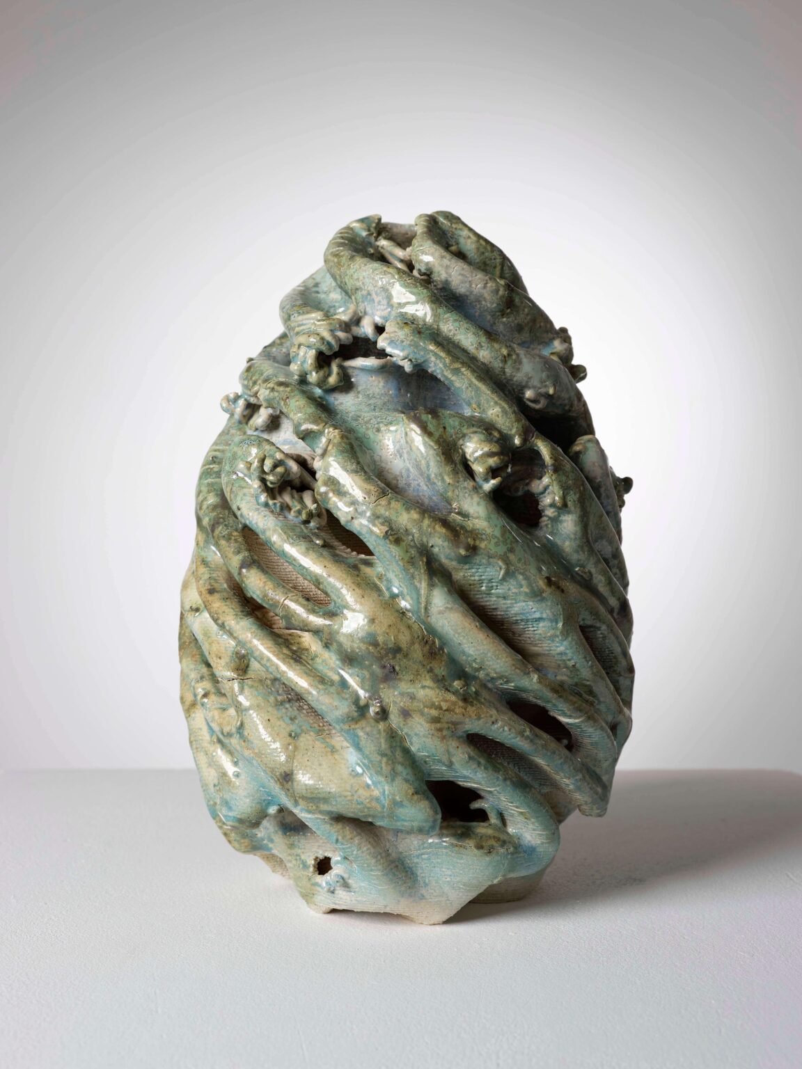Eiförmige Keramikskulptur von Raphaël Emine mit grüner Glasur, dunklen Rissen, farbigen Einschlüssen und durchbrochener Oberfläche.