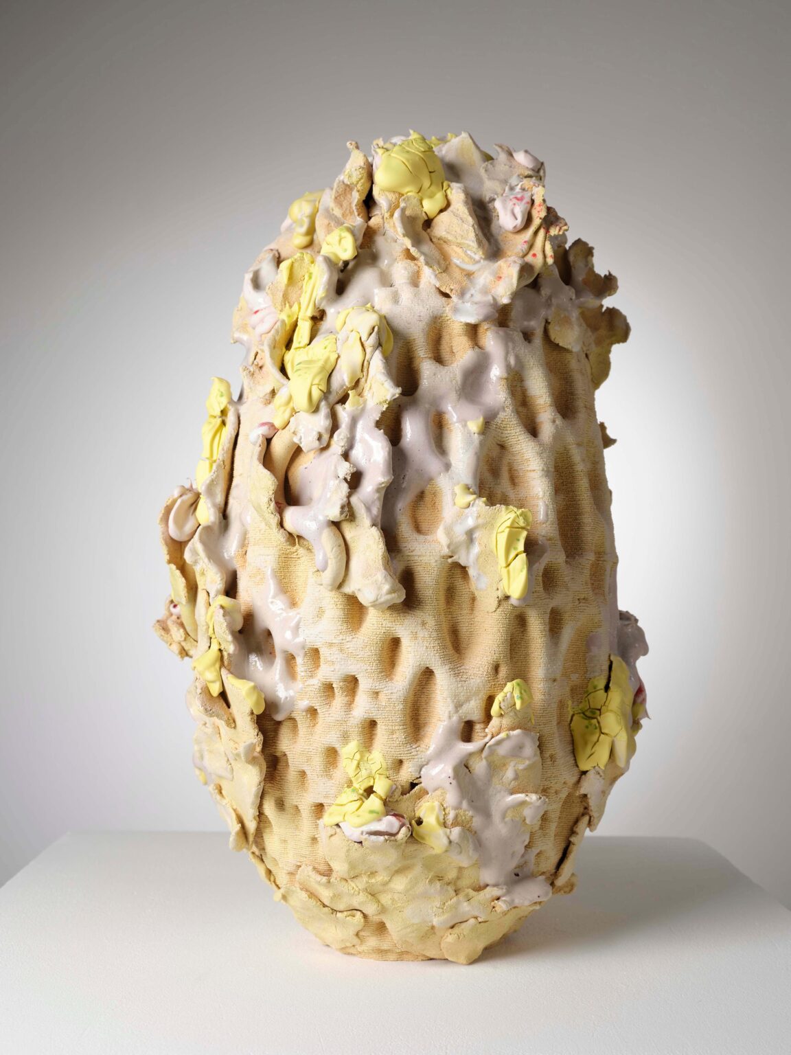 Organische Keramikskulptur von Raphaël Emine mit poröser Struktur, cremefarbenem Körper sowie gelben und roséfarbenen Glasurakzenten.