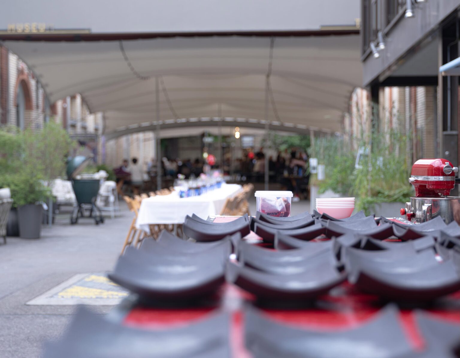 Gestapelte Stühle im Vordergrund mit Blick auf den gedeckten langen Tisch des Pop up Restaurants in der Mühle Tiefenbrunnen bei teo jakob Zürich.