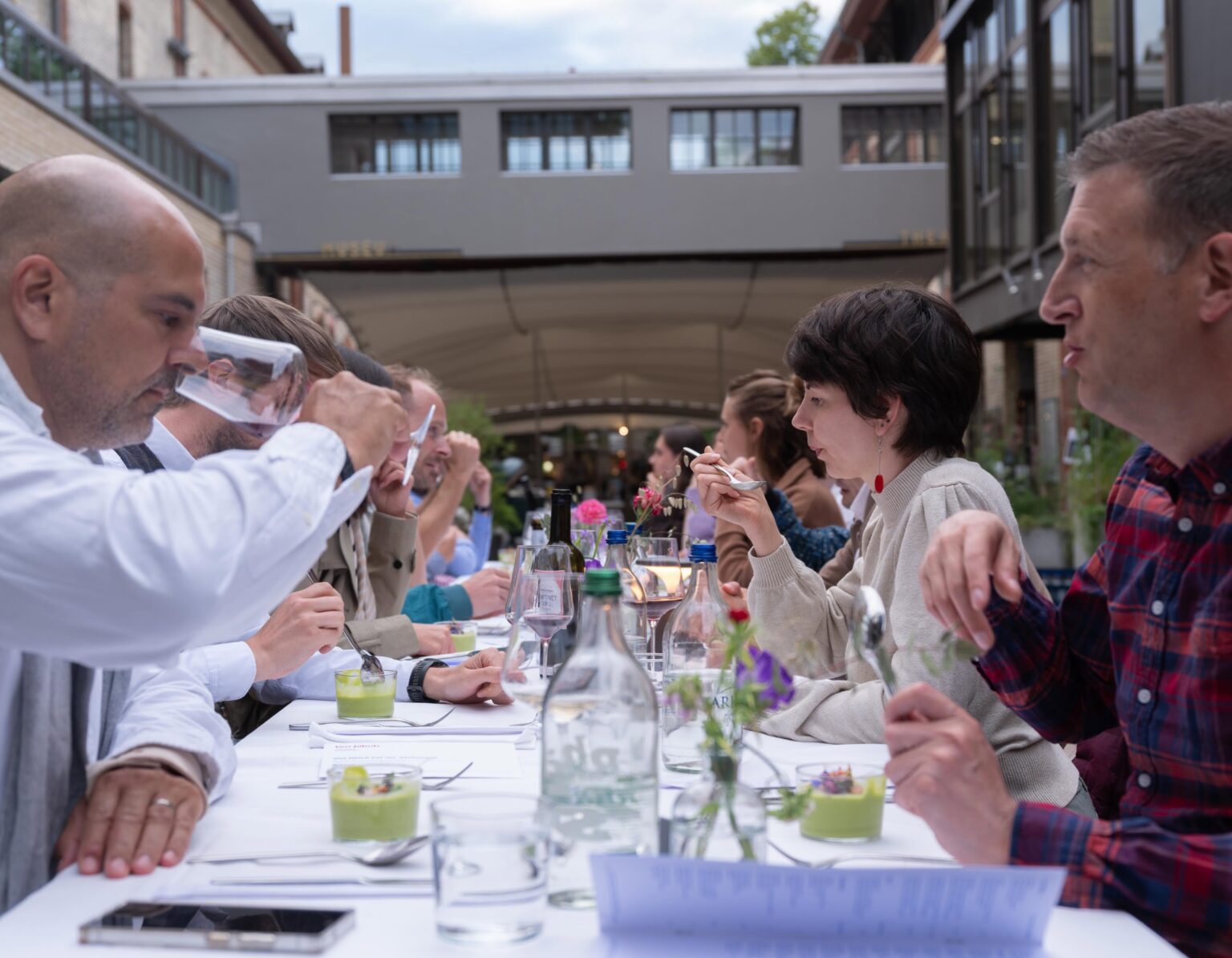 Gäste sitzen an einer langen gedeckten Tafel im Pop up Restaurant in der Mühle Tiefenbrunnen bei teo jakob Zürich.