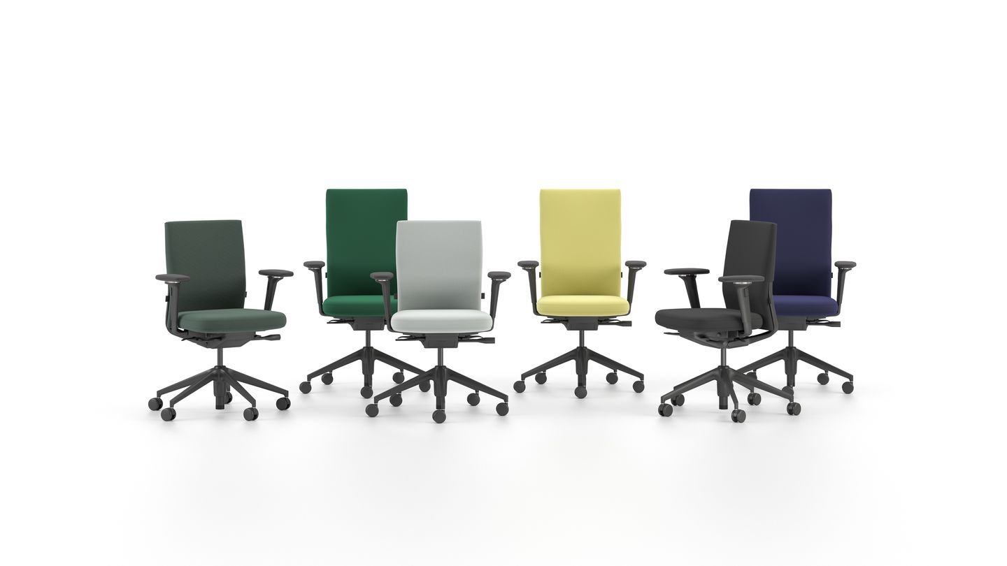 Sechs drehbare Arbeitsstühle gepolstert in Grau, Blau, Grün, Senfgelb und Schwarz, mit schwarzen Armlehnen und Fusskreuzen auf Rollen auf hellem Boden.