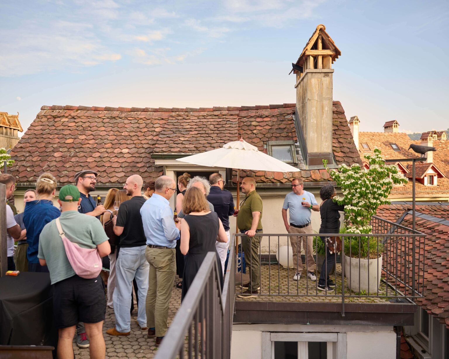 Gäste tauschen sich auf der Dachterrasse von teo jakob Bern während eines Events zum Abbey Stuhl von horgenglarus aus.