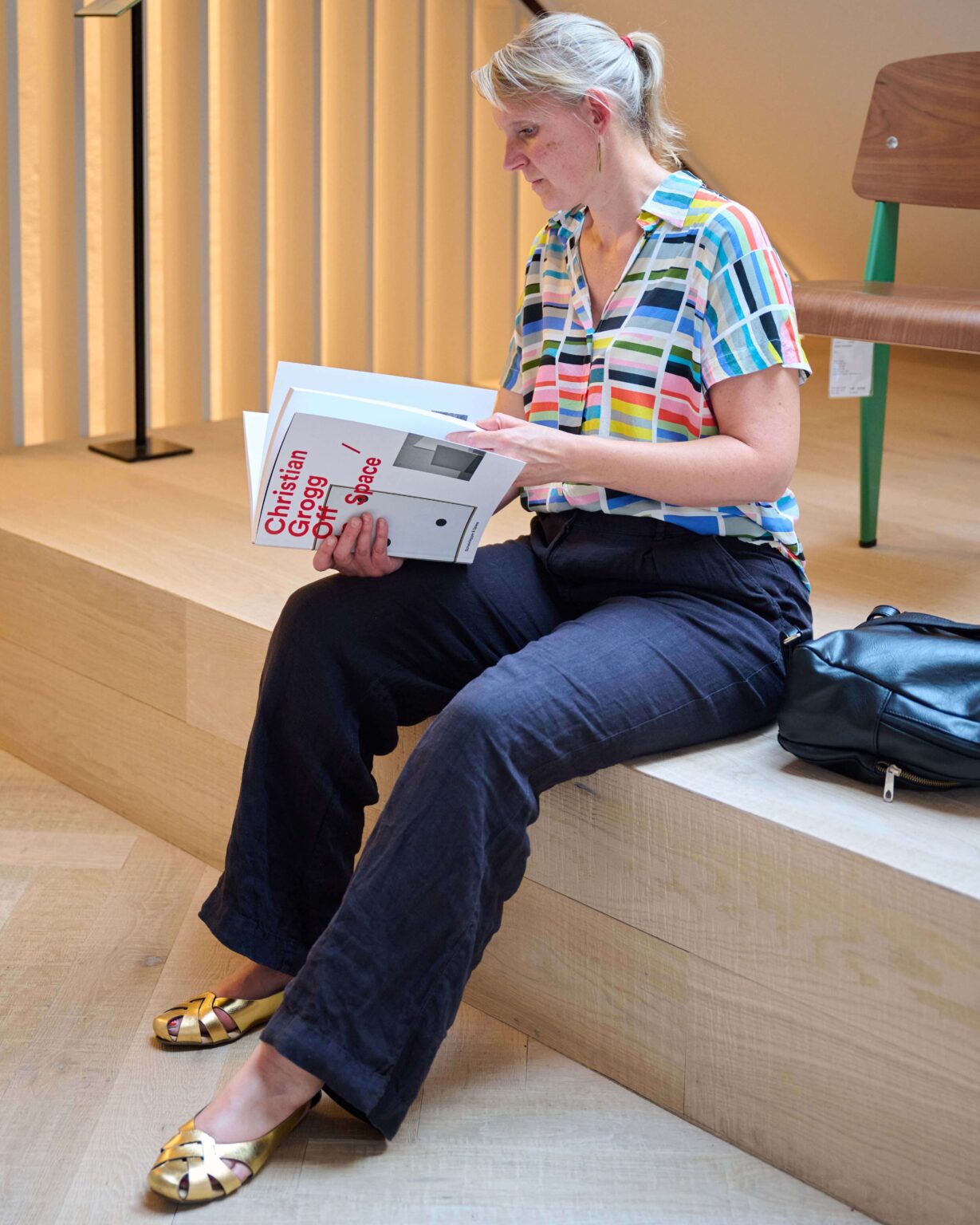 Besucherin liest während eines Events zum Abbey Stuhl von horgenglarus bei teo jakob Bern in einem Designbuch.