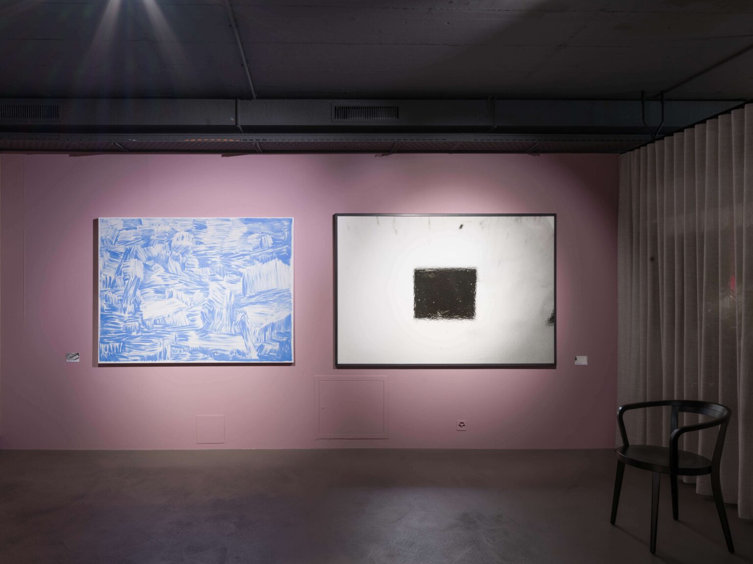 Ausstellungsraum bei teo jakob Bern mit zwei grossformatigen Kunstwerken an rosafarbener Wand und schwarzem Abbey Stuhl von horgenglarus im Raum.